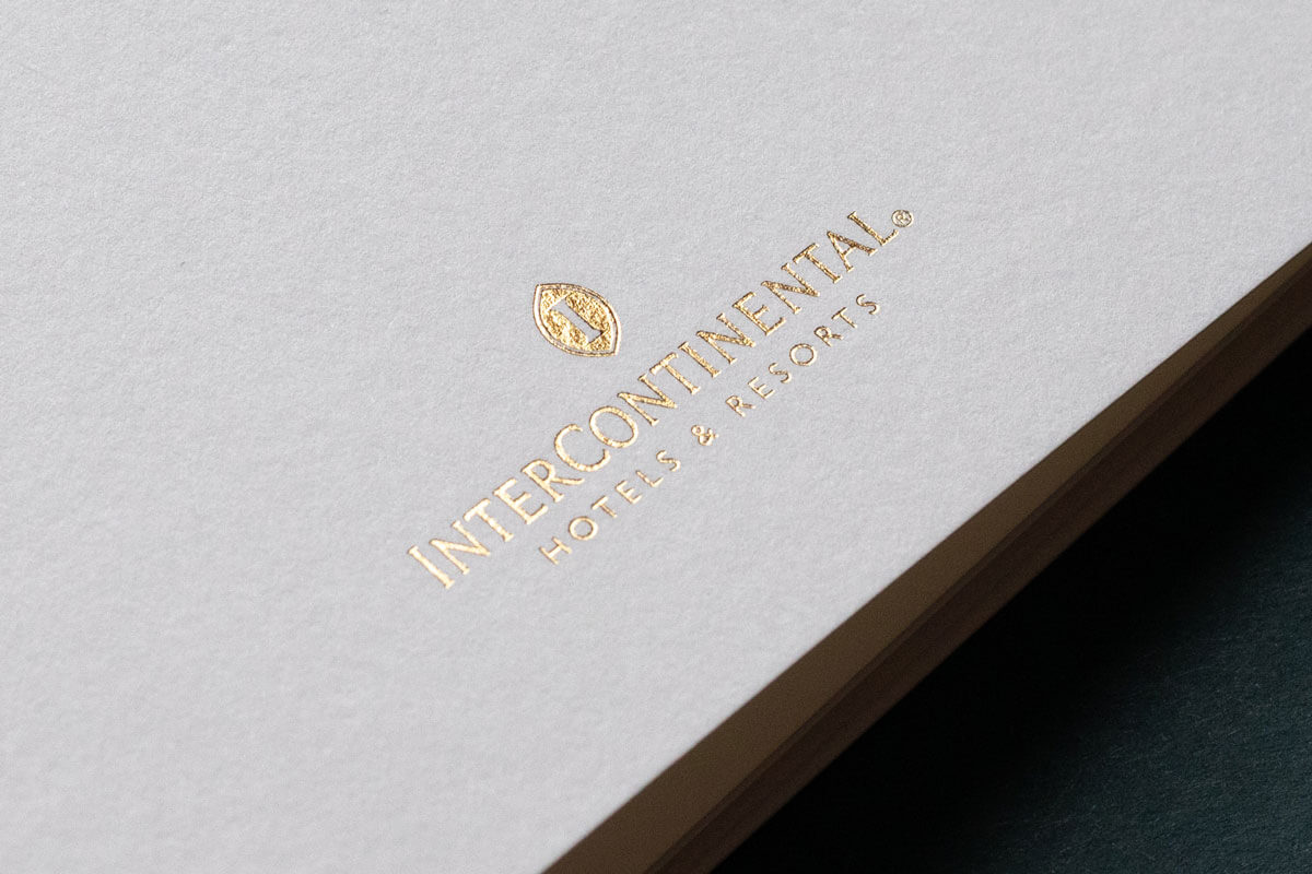 a white brochure with a gold foiled logo of a 5 star hotel brand